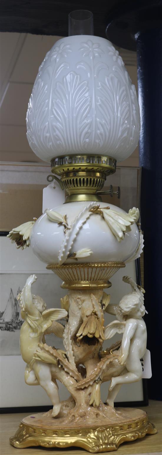 A Moore Bros white, cream and gilt porcelain oil lamp with cherub and flowering cactus support, H 63cm inc shade